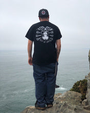 Load image into Gallery viewer, Male wearing tattoo style lady head shirt peering off cliff at ocean.