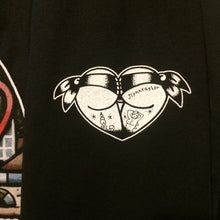 Load image into Gallery viewer, tattoo style butt heart logo on black shirt close up.
